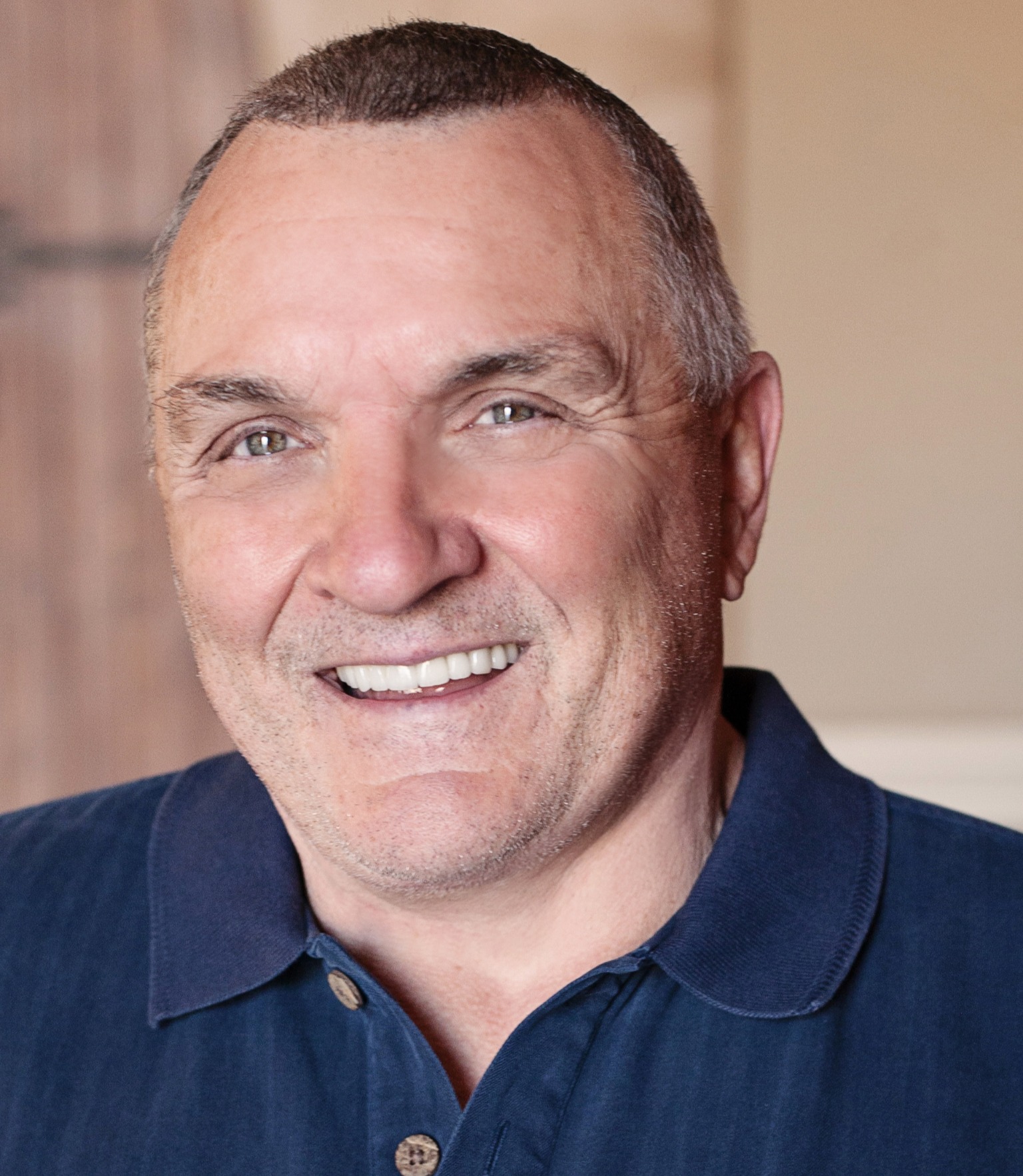 Rudy Ruettiger smiling in a navy polo
